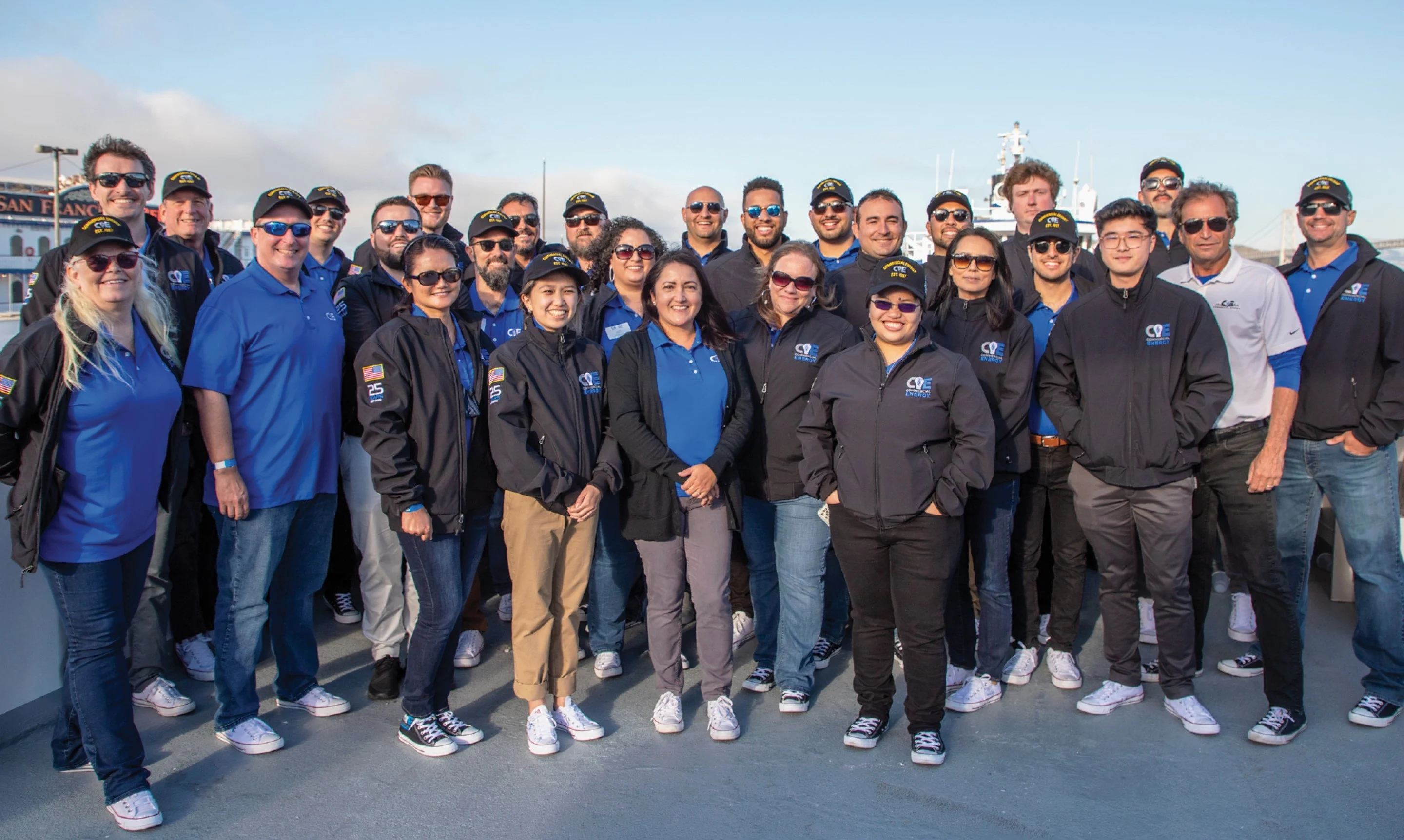 A group of people in blue shirts and black jackets standing in a parking lot